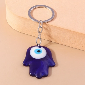 Detail of blue Hamsa Hand and Evil Eye keychain with silver ring on neutral background