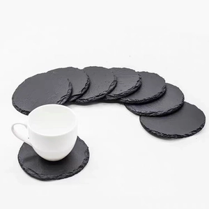 Set of natural black slate coasters with raw edges and a white ceramic teacup on top