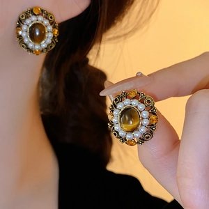 Detail of vintage palace style earrings featuring tiger eye stones and faux pearls