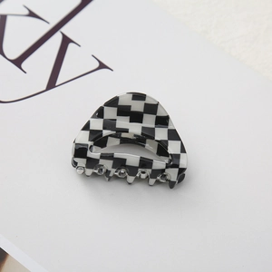 Macro shot of stylish black and white checkerboard hair claw clip with smooth glossy finish