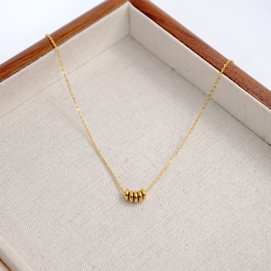 Minimalist gold titanium necklace with five small disc pendants on a fine link chain