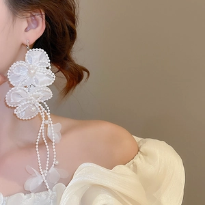 Close-up of white chiffon flower earrings with pearl tassels and delicate bead details