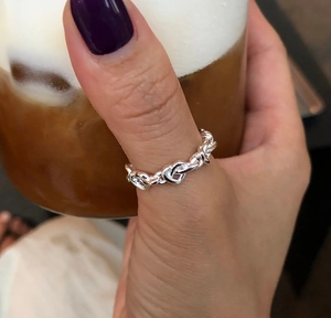 Minimalist 925 sterling silver heart chain ring shown worn on finger in a lifestyle setting