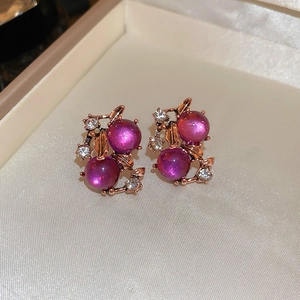 Detailed close-up of floral stud earrings with purple cat-eye stone and rose gold finish
