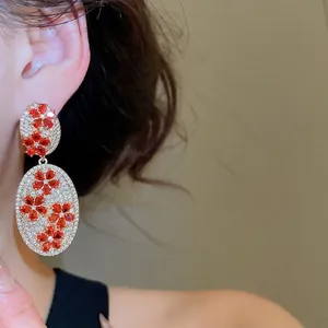 Vintage style gold flower earrings with red gems and white zircons worn by a model