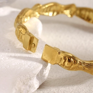Macro view of wave textured 18K gold plated bangle with polished metallic finish