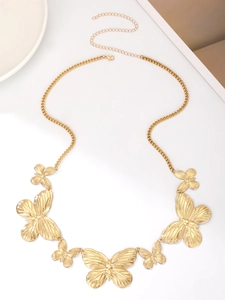 Close-up of golden butterfly body chain with embossed metal wings on white surface