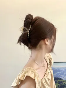 Détail d'une grande pince à cheveux croisée sur cheveux bruns montrant la prise ferme