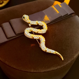 Macro shot of gold-plated snake brooch with sparkling cubic zirconia on brown velvet