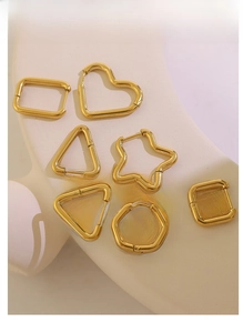 Various gold geometric stainless steel hoop earrings showcased on a minimalist stand