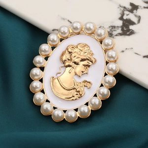 Vintage relief cameo brooch with lady profile portrait and pearl border on green silk fabric