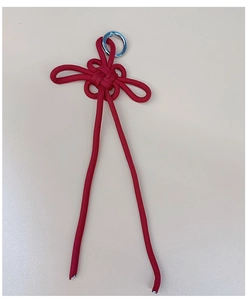 Detailed view of red hand-woven Chinese knot pendant with silver metal spring ring