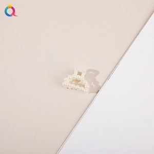 Close-up of elegant white pearl hair claw clip with minimalist design on neutral background