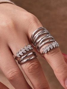 Detailed view of silver wheat-style zircon rings worn on hand with layered design