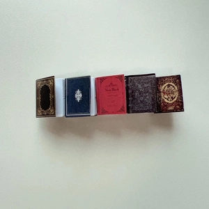 Macro detail of five miniature vintage-style hair clips in diverse antique book colors