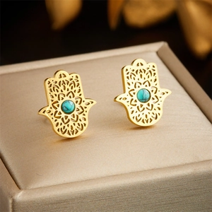 Goldene Hamsa-Hand-Ohrstecker mit Türkis-Inlay auf eleganter Schmuckschatulle