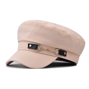 Detailed close-up of beige sailor hat featuring black leather strap and golden heart buckle