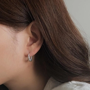Macro shot of silver twisted rope hoop earrings showing minimalist polished texture