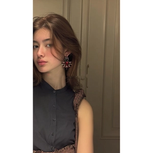 Vue détaillée de boucles d'oreilles fleurs vintage avec pierres rouges et sombres sur modèle