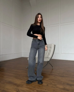 Détail d'un jean vintage gris délavé à taille basse porté avec un haut court noir