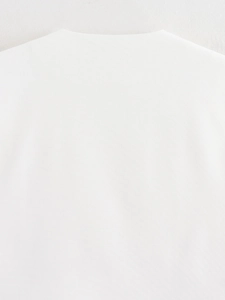 Detail of white V-neck cardigan vest showing the collar stitching and fabric texture