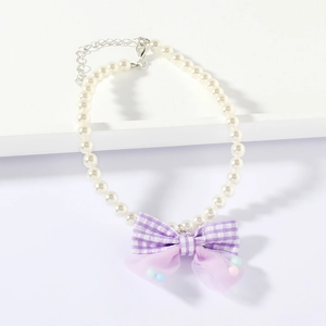 Close-up of pearl pet necklace with purple plaid bow and metal extension chain detail