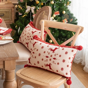 Detailed knit of festive beige Christmas pillows with red reindeer and snowflake patterns