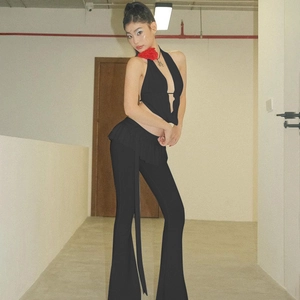Vista laterale dei pantaloni svasati neri e top con accessorio girocollo fiore rosso