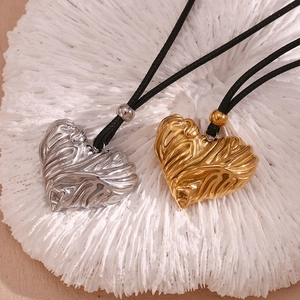 Close-up of heart pendants with wrinkled texture in gold and silver on black cord