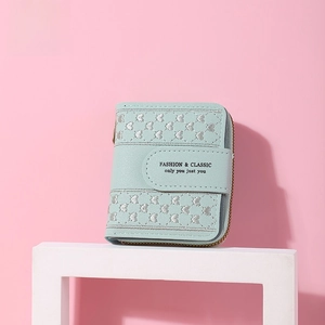 Detail of mint green zippered wallet with silver heart embroidery on display stand