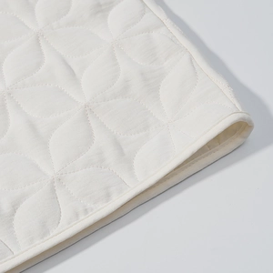 Detailed macro view of white quilted jacket with floral diamond patterns and fine stitching
