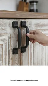 Detail of vintage black cast iron door handles installed on rustic white wooden cabinets
