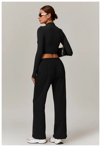Detail view of black high-waist wide-leg track pants with a central crease and elastic waist