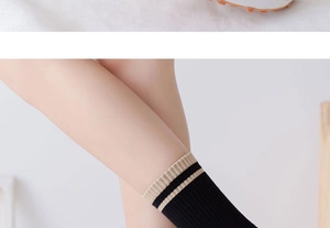 Close-up of black cotton mid-calf socks featuring beige stripes on the ribbed cuffs