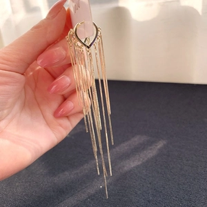 Close-up of golden heart tassel earrings with long chain fringe on a display card