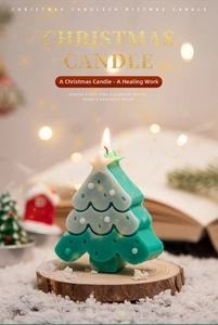 Close-up of a green and white Christmas tree candle on a wooden base with warm lights