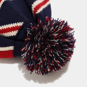 Dettaglio di un caldo berretto invernale in maglia con un pompon tricolore sulla cima
