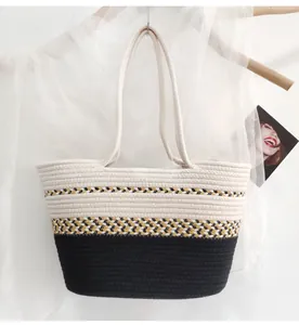 Detail of color-block woven tote bag made of cotton rope hanging on a wooden stand