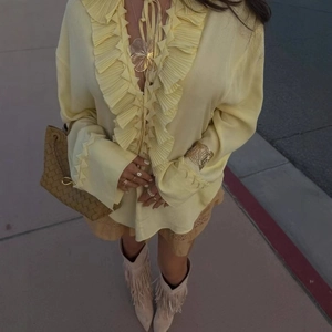 Pale yellow ruffled blouse with drawstring details and high-shine silk-like fabric