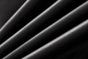 Close-up of black faux leather aviator jacket texture showing refined grain and subtle gloss