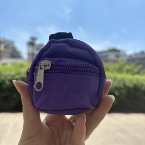 Handheld view of a purple mini backpack keychain coin purse with textured canvas material