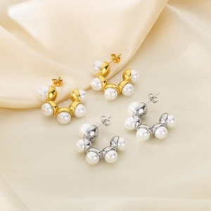 Détail macro de boucles d'oreilles créoles en acier doré et argenté avec perles