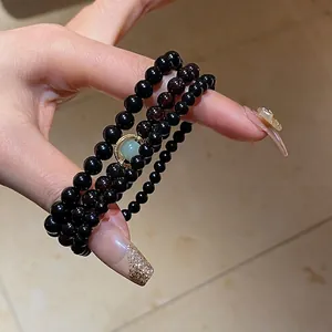 Three-layer black obsidian beaded bracelet with gold-rimmed green chalcedony bead