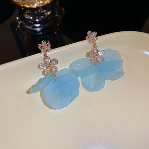 Détails macro de boucles d'oreilles pétales bleues avec diamants sur plateau céramique