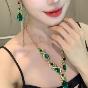 Elegant gold necklace and earring set with green teardrop zircon gems on a model