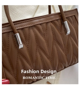 Close-up of a dark brown pleated leather handbag with wavy quilted texture and silver hardware