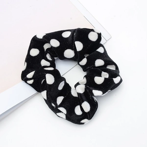 Polka dot pattern scrunchie in black and white velvet fabric on a clean background