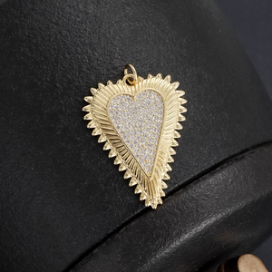 Macro detail of 18K gold plated heart pendant with cubic zirconia and sunburst texture