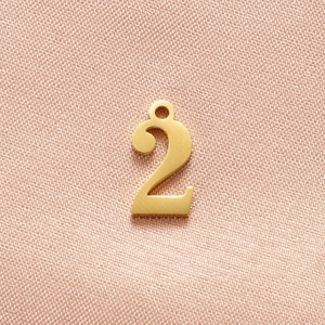 Macro shot of gold number 2 charm with brushed texture for DIY jewelry making