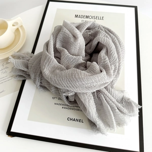 Detail of grey crinkle cotton linen shawl featuring natural raw edges and breathable texture